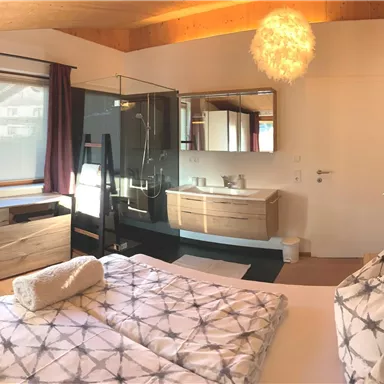 A modern bedroom with a large bed and stylish furniture. The large window front lets in a lot of light and offers a view of the surroundings.