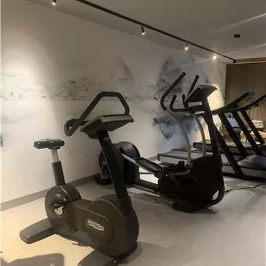 A modern fitness room with various training equipment. The walls are adorned with a calming, graphic design.