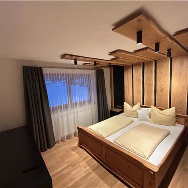 Ein stilvolles Schlafzimmer mit zwei Betten und Holzdetails. Große Fenster lassen natürliches Licht herein.