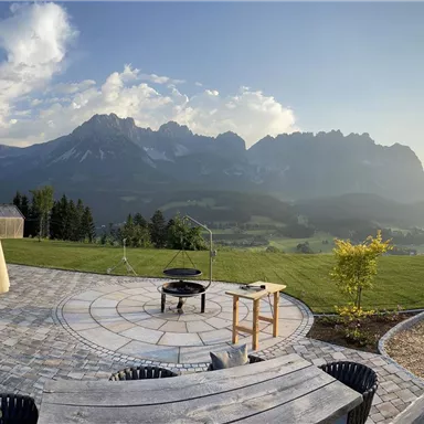A picturesque view of the mountains at sunset. The patio is cozy furnished with furniture and a swimming pool.