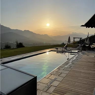 A pool with a view of the mountains at sunset. The atmosphere is calm and relaxing.