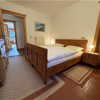 A cozy bedroom with a wooden bed and nightstands. The room has a warm, inviting feel and is well-lit.