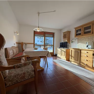 A cozy holiday apartment with wooden details and plenty of natural light. The living area includes a dining space and a small kitchen.