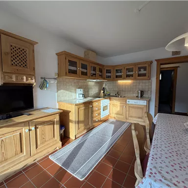A cozy kitchen with wooden cabinets and modern amenities. The table is set for a meal and the room is bright and inviting.