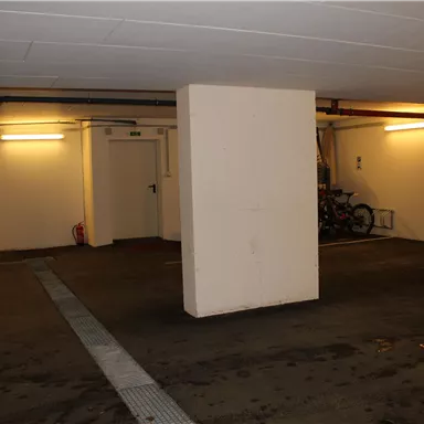 An empty parking lot with a column in the middle. The walls are light and the lighting is soft.