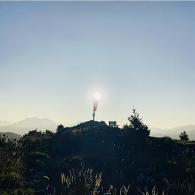 A splendid mountain landscape in sunlight with a red windsock. In the background, some mountains and a clear sky can be seen.