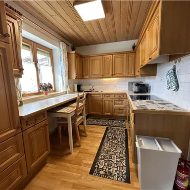 Eine gemütliche Küche mit Holzschränken und einem hellen Raum. Der Tisch und die Stühle bieten Platz zum Essen und Verweilen.