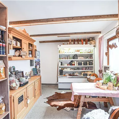 A cozy sales area with shelves full of food and drinks. Fresh products and plants are on the table.