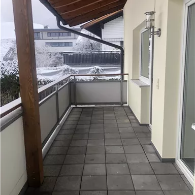 A spacious balcony with an overhang and light tiles. In the background, snow-covered landscapes can be seen.