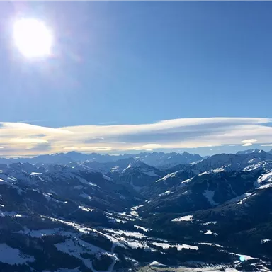An impressive mountain landscape under a radiant blue sky. The snow-capped peaks reflect the sunlight, creating a picturesque view.