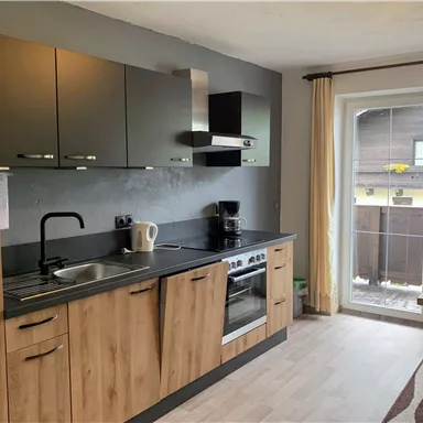 Eine moderne Küche mit Holz- und Metallelementen. Am Fenster gibt es einen schönen Blick nach draußen.