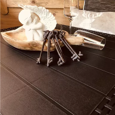 Ein dekoratives Arrangement auf einem Tisch mit einem geschwungenen Holzobjekt, einer Figur und mehreren alten Schlüsseln. Im Hintergrund sieht man Gläser und einen hellen Raum.