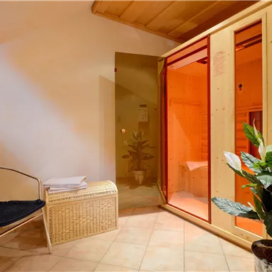 A relaxing wellness area with a sauna and cozy seating. Plants and warm light create a pleasant atmosphere.