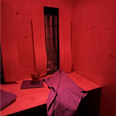 A cozy room with red light. On a table, there is a towel and a cup.