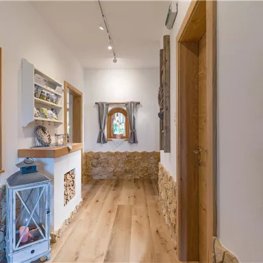 Ein einladender Flur mit Holzdetails und einer warmen Atmosphäre. An den Wänden sind dekorative Elemente und ein Fenster mit Vorhängen zu sehen.