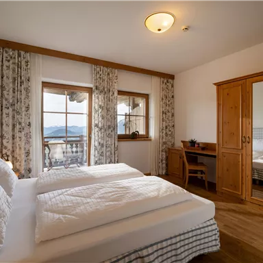 Ein gemütliches Schlafzimmer mit zwei Betten und Holz furnishings. Große Fenster bieten einen schönen Blick auf die umliegende Landschaft.