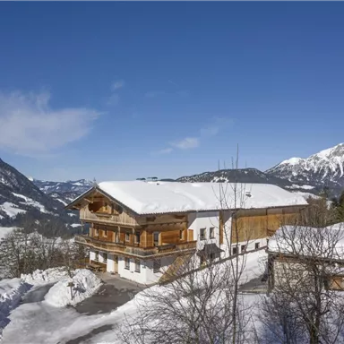 Ein gemütliches Chalet im Schnee mit atemberaubendem Blick auf die Berge. Der strahlend blaue Himmel ergänzt die winterliche Landschaft.