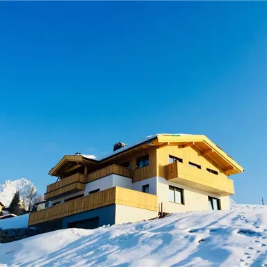 A modern house with yellow wooden cladding in a snowy landscape. The clear blue sky forms a beautiful background.