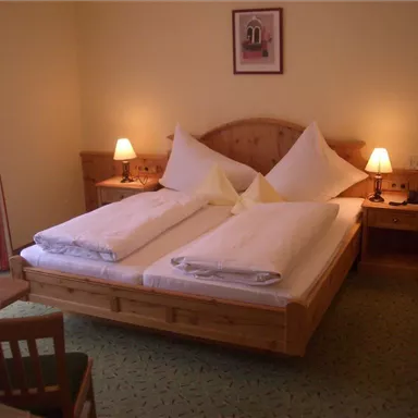 Ein gemütliches Schlafzimmer mit einem großen Doppelbett und zwei Nachttischen. Die Wände sind in sanften Farben gehalten, und es gibt ein Fenster mit Vorhängen.