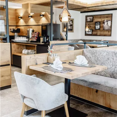 A modern restaurant with wooden interiors and cozy seating. The table is nicely set with cloth napkins.