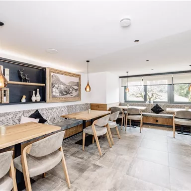 A modern restaurant with wooden tables and comfortable chairs. Large windows provide plenty of natural light and a welcoming atmosphere.