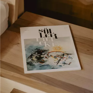A notebook lies on a wooden table. The cover page features an artistic illustration and the title "Südlüft".