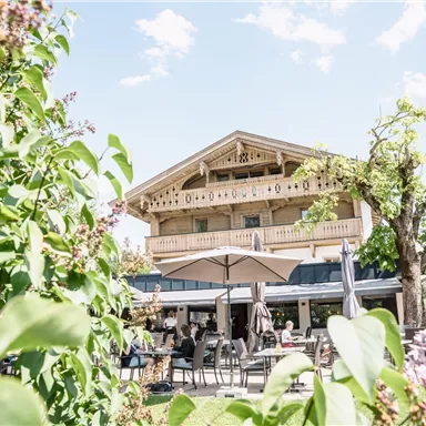 A cozy restaurant with an outdoor terrace. Surrounded by trees and plants on a sunny day.
