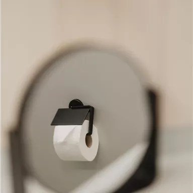 An elegant toilet paper holder with a roll of toilet paper. The holder features a modern and minimalist design.
