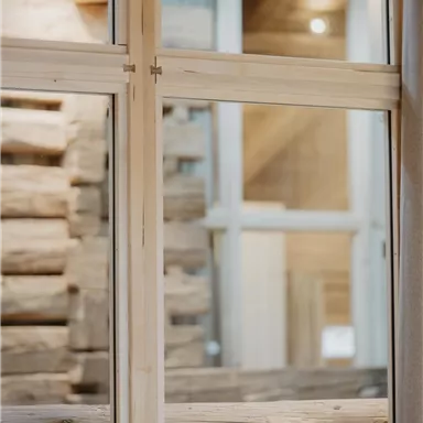 A view through a large window onto a rustic wooden structure. The warm wood look creates a cozy atmosphere.