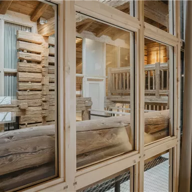 A cozy room with wooden interior and large windows. The decor exudes a rustic yet modern charm.