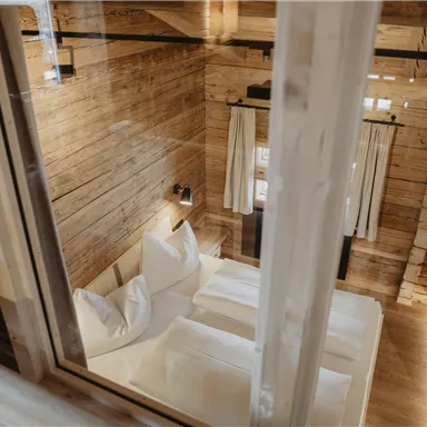 A cozy bedroom in a wooden house. The decor is simple and modern with two beds and large windows.