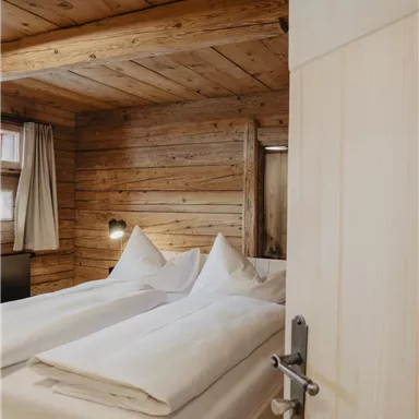 A cozy bedroom with wood paneling and a double bed. The soft lighting creates an inviting atmosphere.