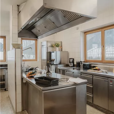 A modern kitchen with stainless steel appliances and a spacious work area. Large windows provide plenty of daylight.