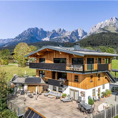 A modern wooden house surrounded by beautiful scenery and majestic mountains. The terrace offers a magnificent view of nature.