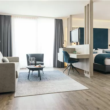 A modern hotel room with a comfortable sofa and a large window that lets in plenty of light. The elegant decor and calm colors create an inviting atmosphere.