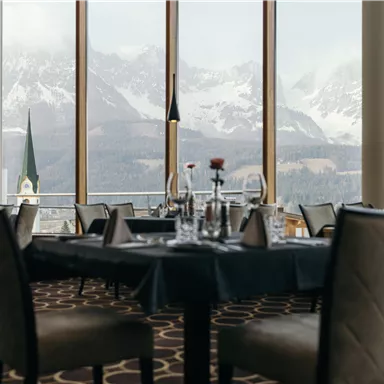 An elegant restaurant with a view of snow-capped mountains. The tables are tastefully set, and large windows let in plenty of light.