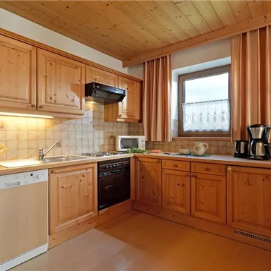 A cozy kitchen with wooden cabinets and modern appliances. The windows let in a lot of natural light.