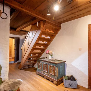 A cozy hallway with a wooden staircase and rustic furniture. The room has warm colors and an inviting atmosphere.