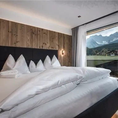 Ein modernes Schlafzimmer mit Holzverkleidung und einem großen Fenster. Der Blick auf die Berge und die schöne Natur sorgt für eine entspannende Atmosphäre.