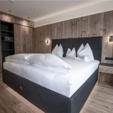 Ein modernes Schlafzimmer mit einem großen Bett und Holzvertäfelungen. Der Raum ist freundlich und einladend eingerichtet.