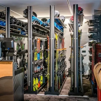 A ski rental with a large selection of skis and snowboards. In the foreground, there is a reception desk.