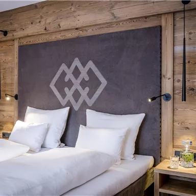 A modern bedroom with two beds and wood paneling. The walls are warm and inviting, with soft lighting.