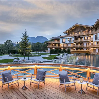 A stylish chalet by the lake with modern wooden balconies. The view of the surrounding mountains and the well-kept garden creates a relaxed atmosphere.