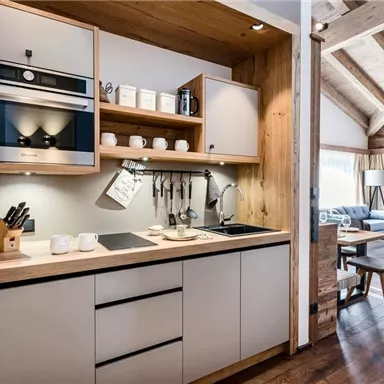 A modern kitchen with wooden cladding and a cozy decor. It features high-quality kitchen appliances and an inviting dining area.