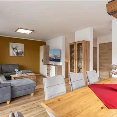 A modern living room with a comfortable gray sofa and a wood-covered table. The room has a warm atmosphere and a clear, bright decor.