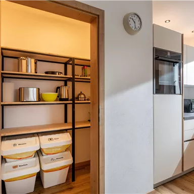 A modern kitchen with an open shelf. On the shelf, various cooking utensils and containers are lined up.