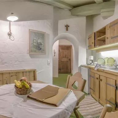 Eine gemütliche Wohnküche mit Holzmöbeln und einem runden Esstisch. Die Wände sind hell und die Atmosphäre ist einladend.