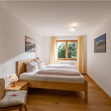 Ein gemütliches Zimmer mit zwei Betten und einem Fenster, das Blick auf die Natur bietet. Der Raum ist hell und freundlich eingerichtet.