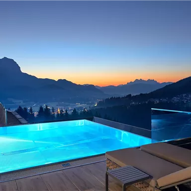 A beautiful infinity pool with mountain views at sunset. The scene exudes tranquility and elegance.