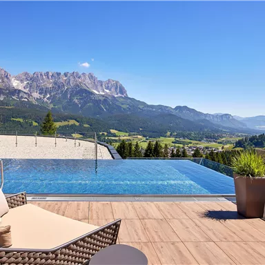 A modern terrace with an infinity pool and stunning mountain views. The sunny surroundings invite relaxation.